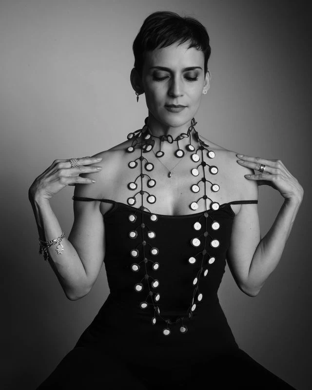 Retrato en blanco y negro con collar y ojos cerrados.