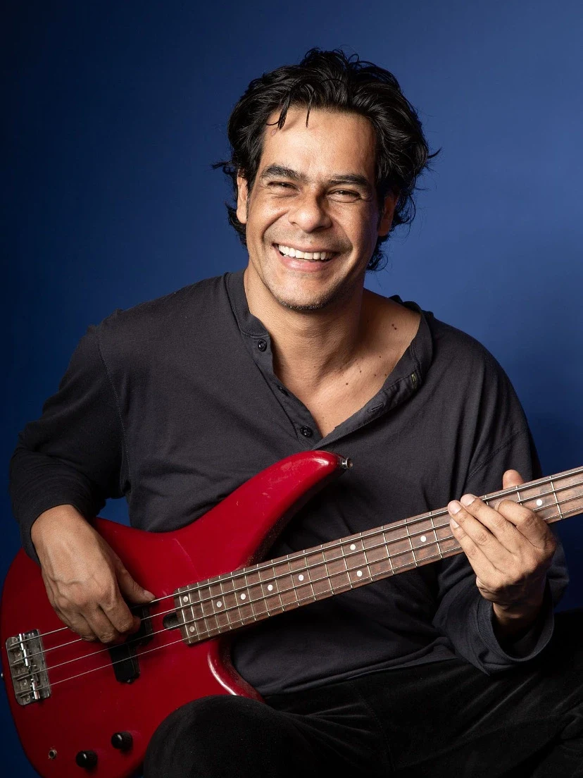 Retrato con bajo eléctrico rojo sobre fondo azul.