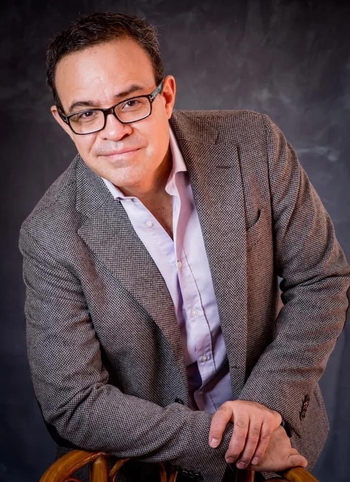 Retrato masculino con saco gris y anteojos.