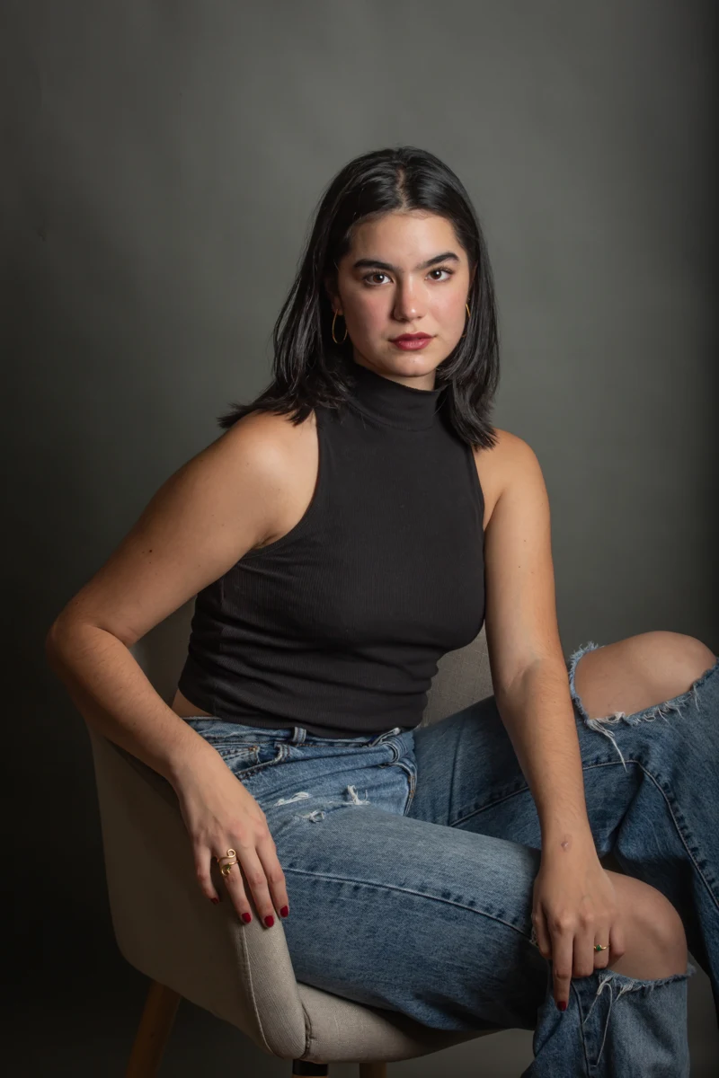 Retrato sentado con blusa negra y jeans.