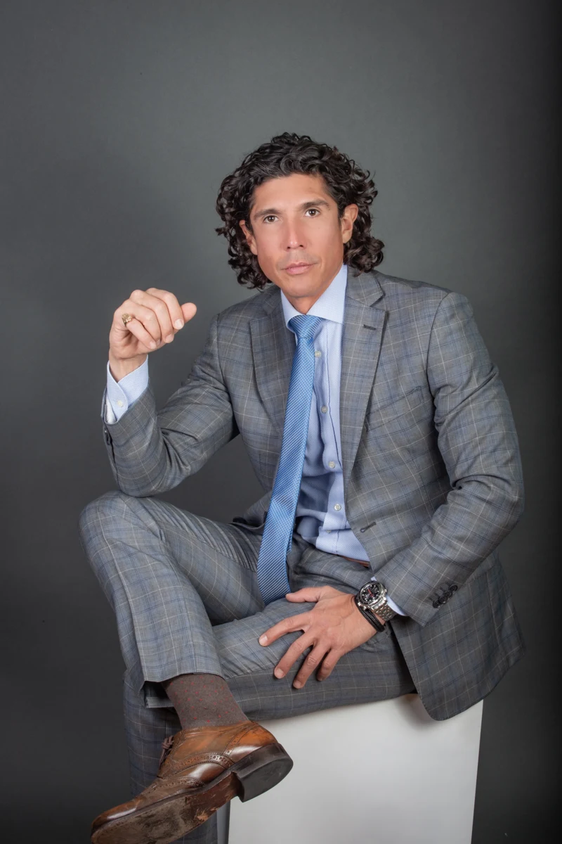 Retrato masculino sentado con traje gris.