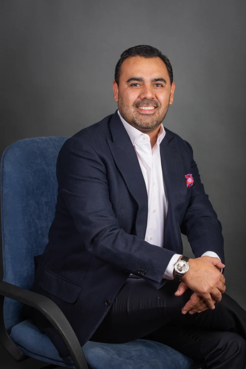 Retrato masculino sentado con traje y corbata.