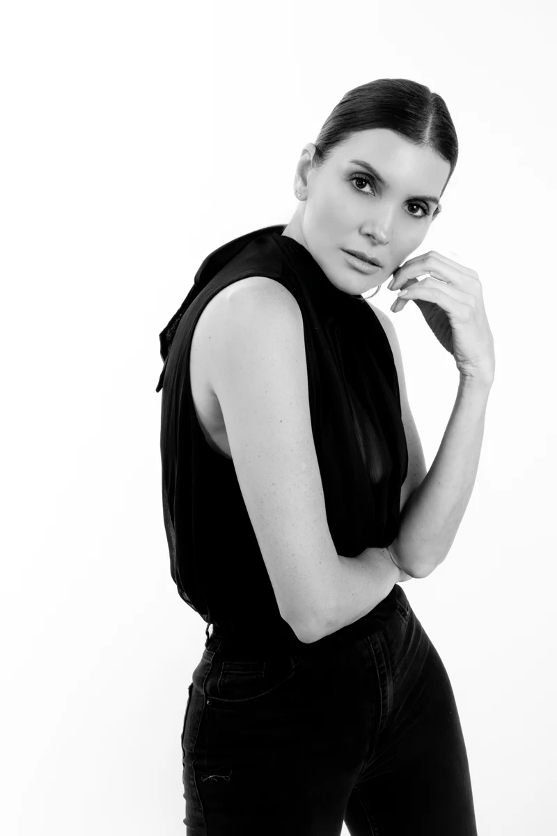 Retrato con blusa negra y mirada a cámara.