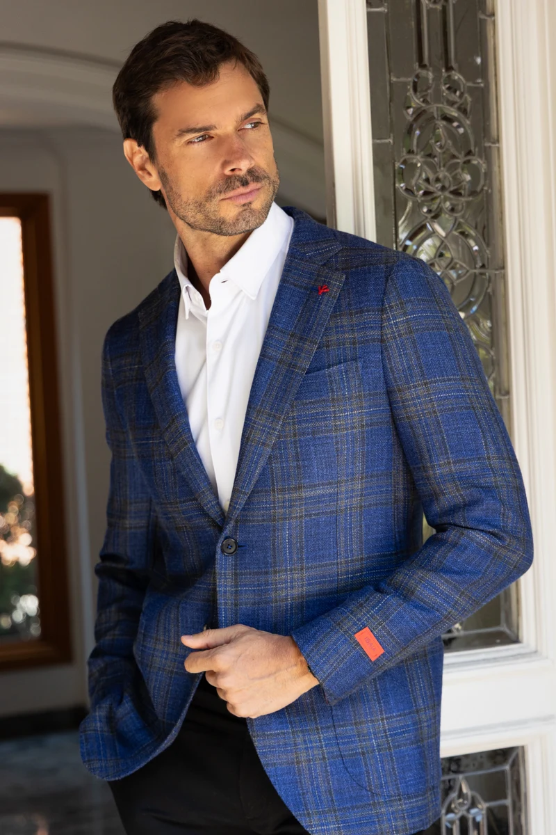 Retrato masculino con traje azul junto a una puerta.