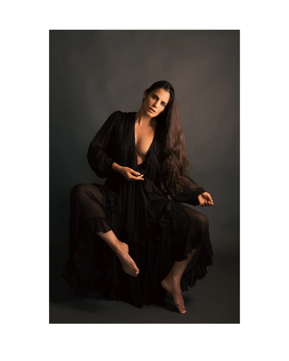 Retrato sentado con vestido negro y fondo oscuro.