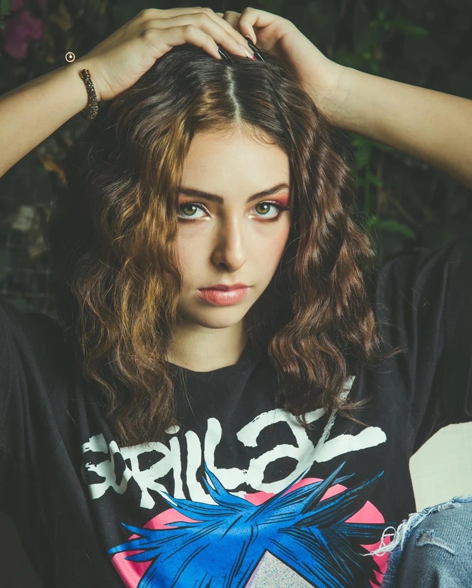 Retrato con camiseta estampada y manos sobre el cabello.