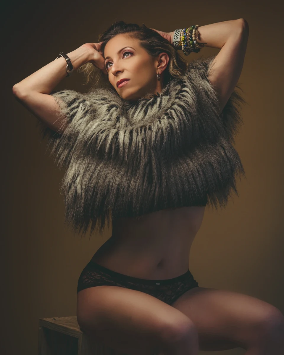 Retrato con prenda de plumas y brazos elevados.