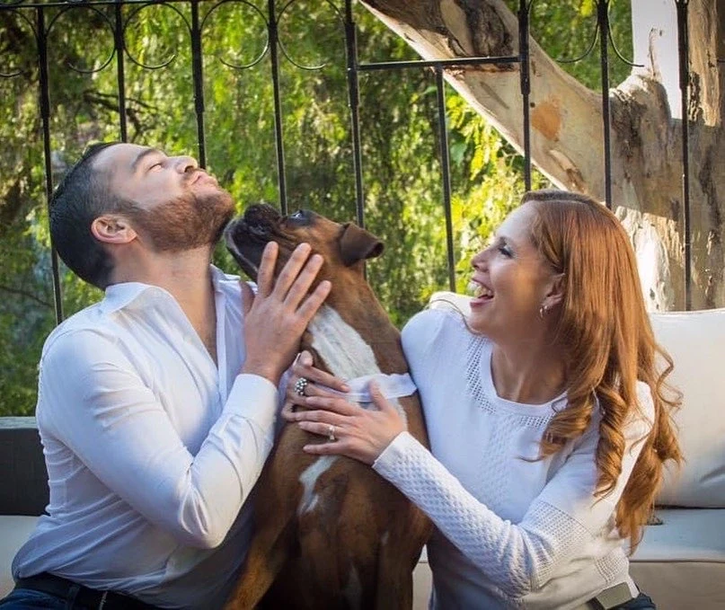 Retrato de una pareja con su perro en exterior.